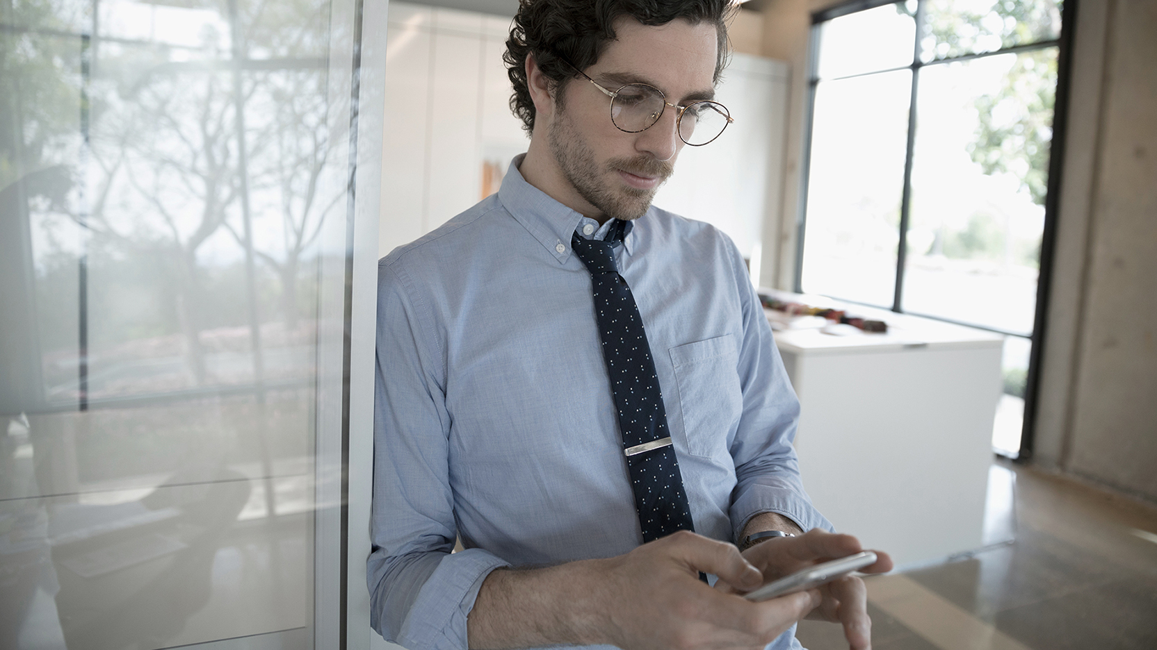 Male in shirt and tie looking at smartphone 